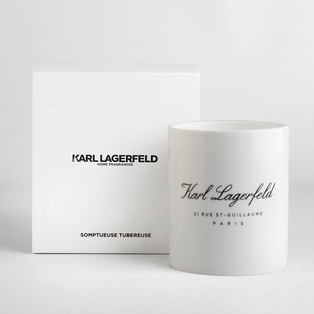 A white fine bone china candle with 'KARL LAGERFELD' printed in black script, accompanied by its packaging.